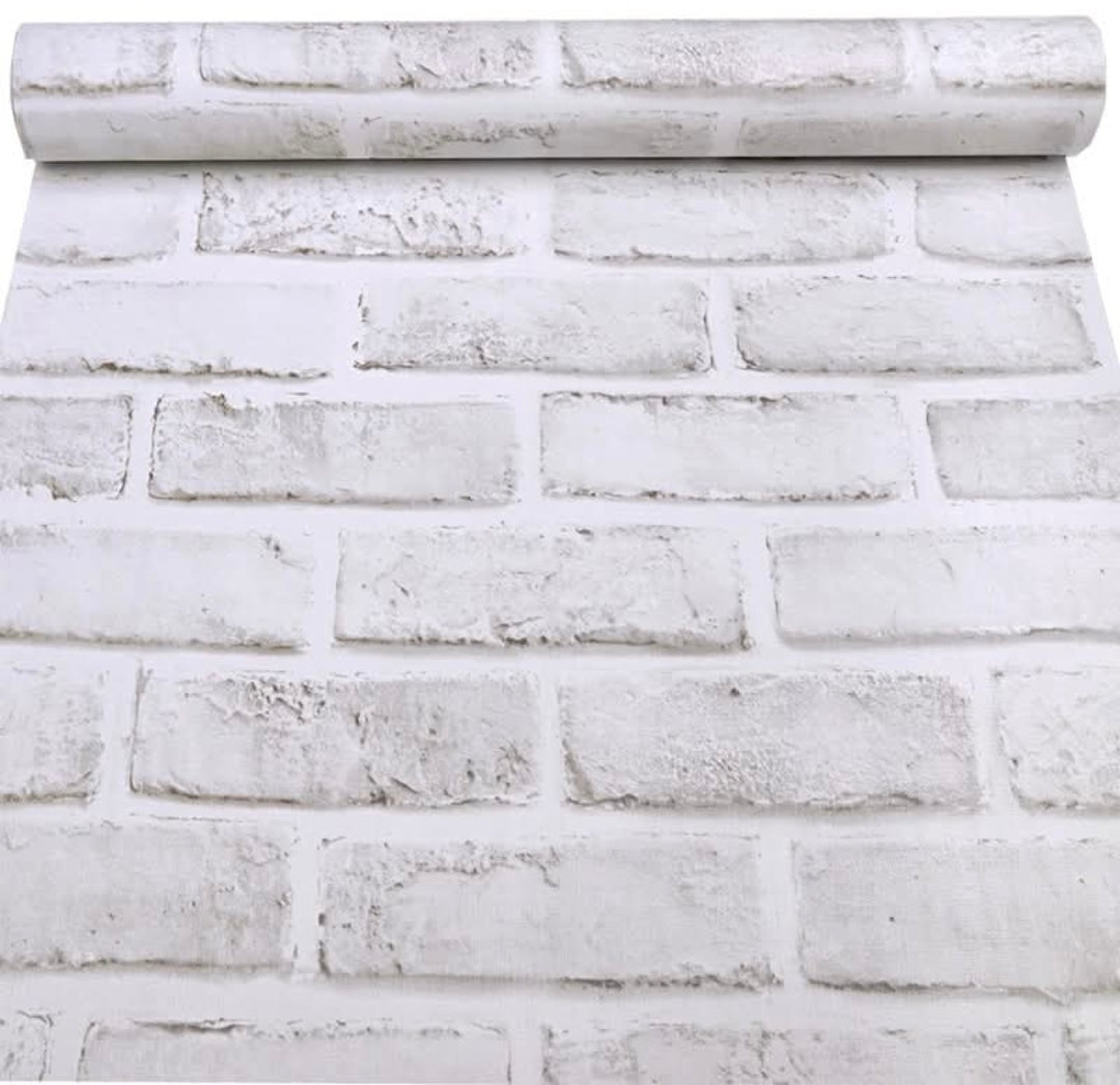 White brick self-adhesive wallpaper roll by Budget Interiors, shown rolled out with textured brick pattern on smooth surface.